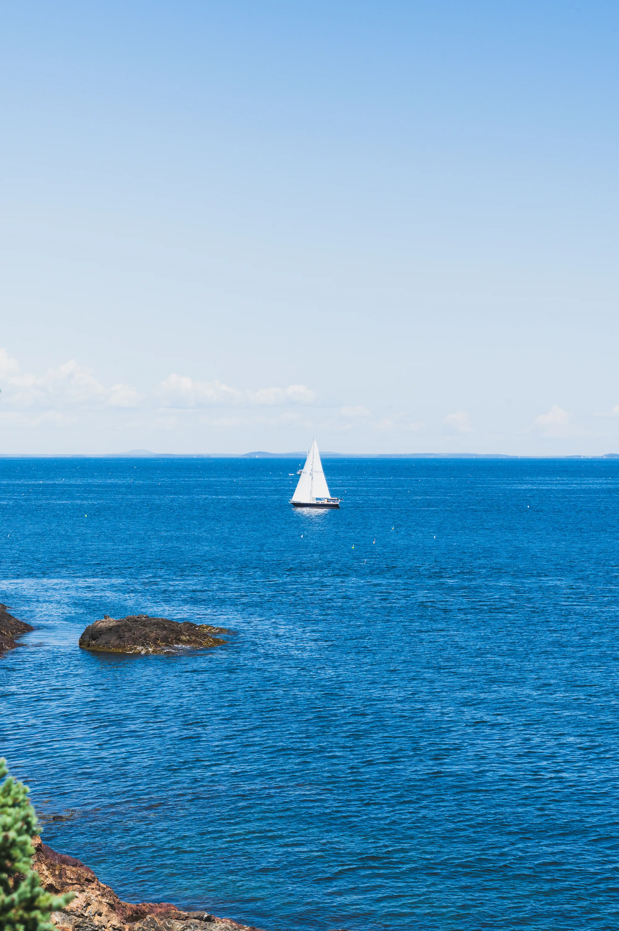a sailboat floats in a blue-green coast